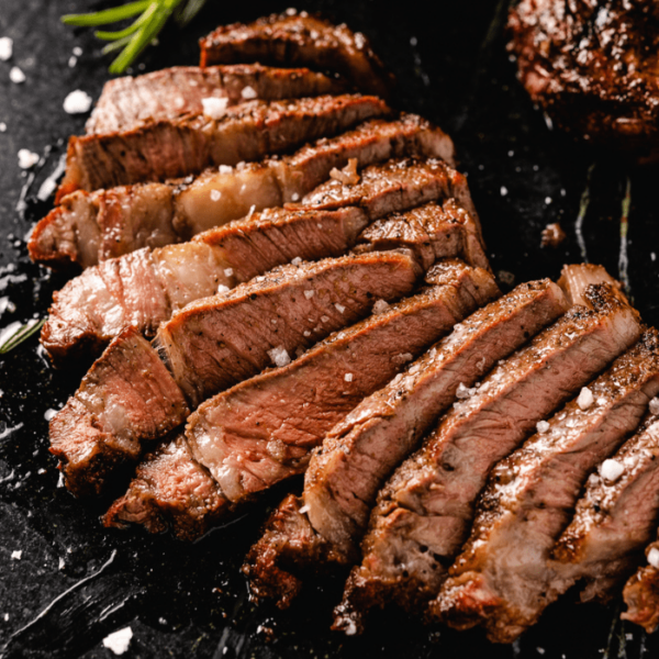 Reverse sear ribeye steak sliced on a serving board.