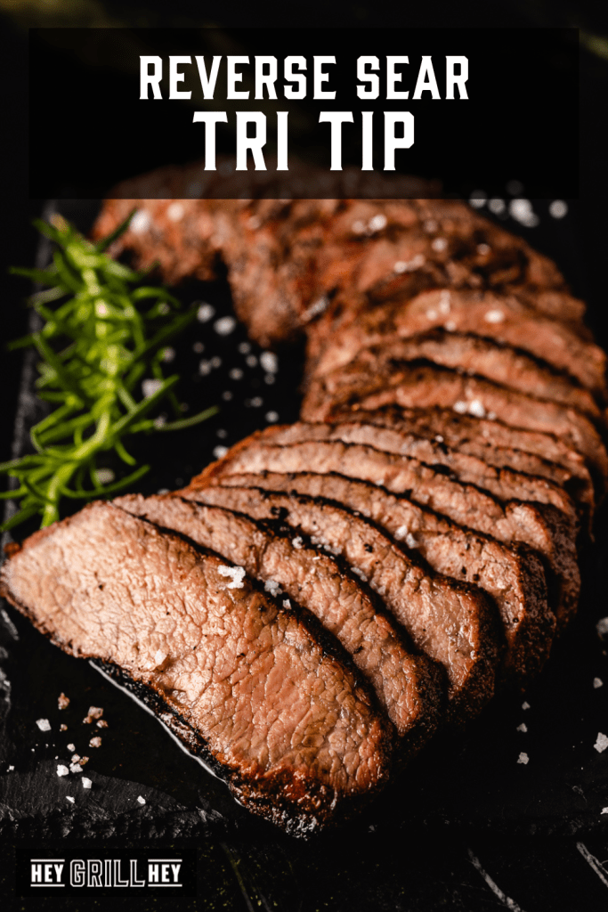 Sliced tri tip roast on a black serving platter with text overlay - Reverse Sear Tri Tip.
