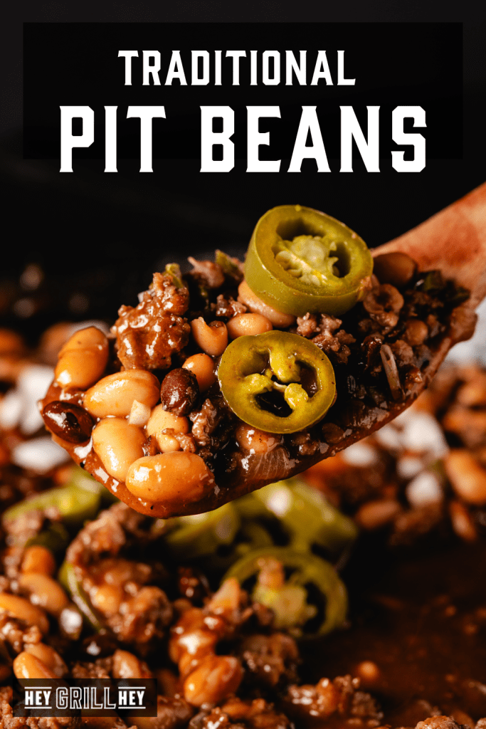 Wooden spoon lifting pit beans topped with jalapenos out of a cast iron skillet.