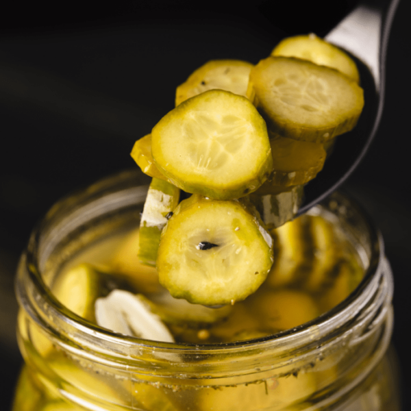 Quick pickles being scooped out of a glass mason jar.