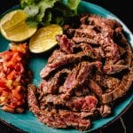 Sliced carne asada on a blue plate.