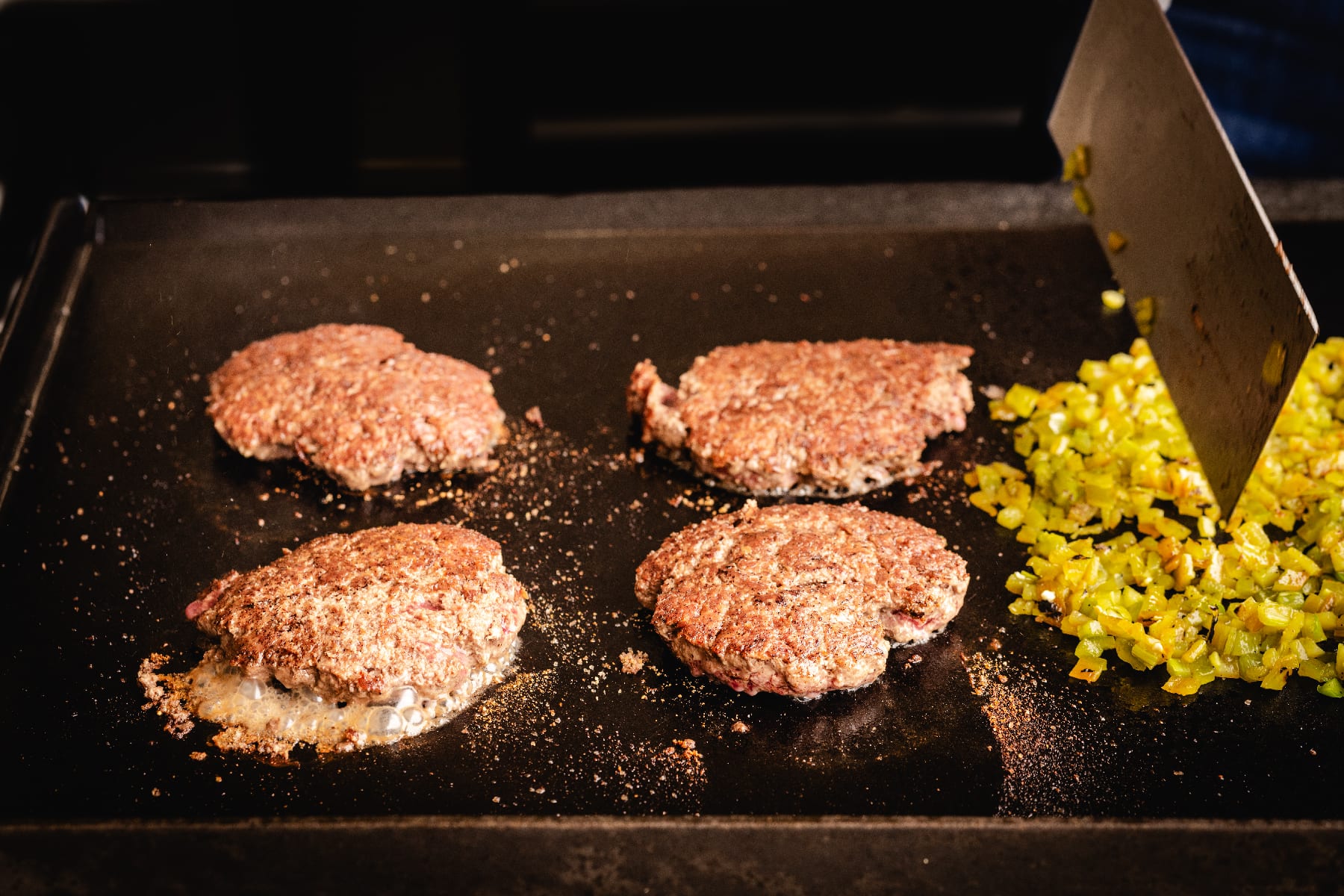 Burger patties and diced Hatch chiles on griddle.