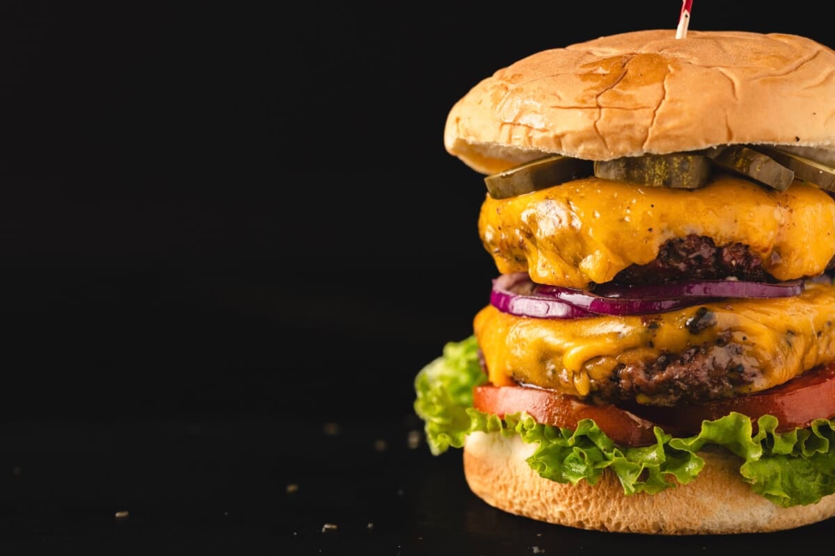 Assembled burger on black background.