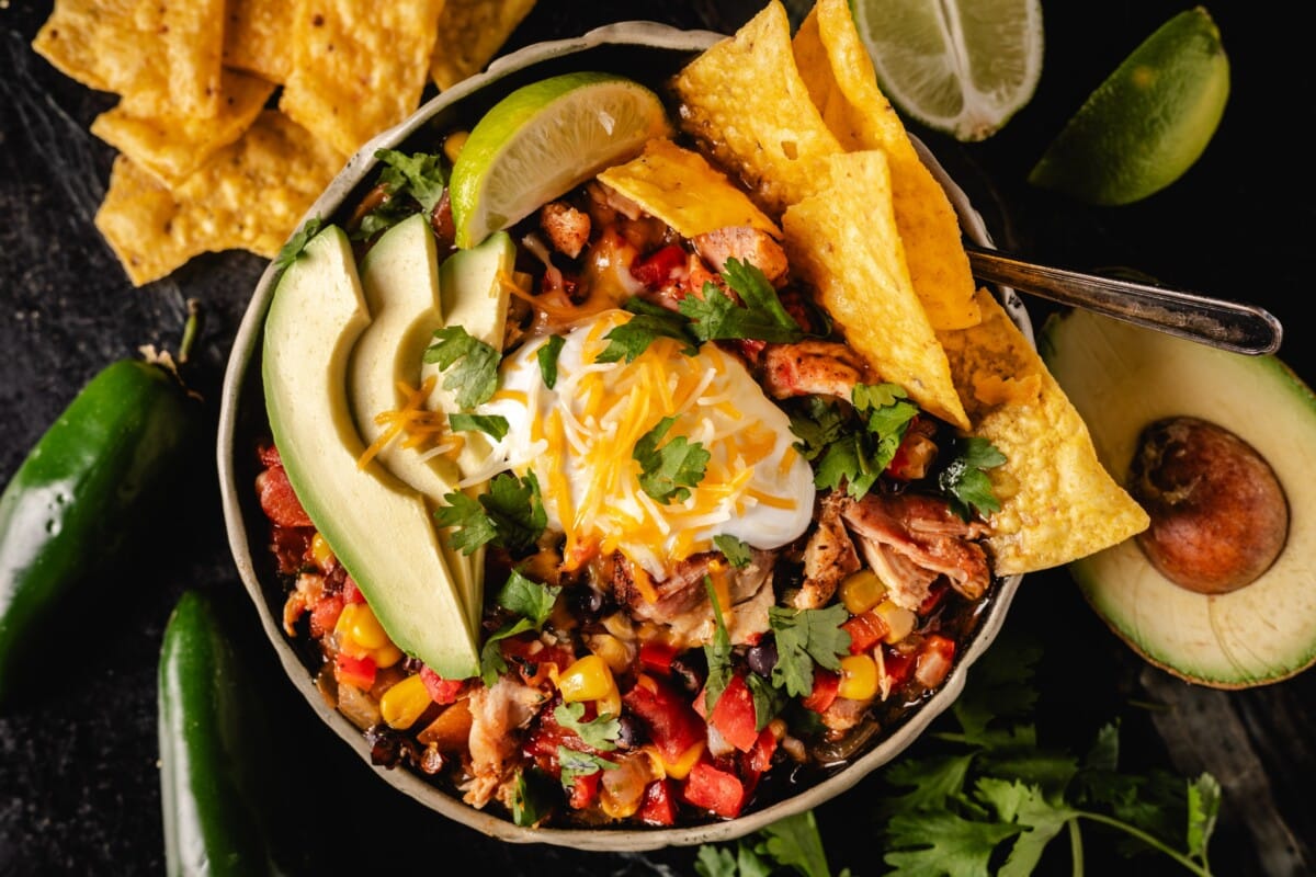 Chicken Tortilla Soup in a bowl garnished with tortilla chips and avocado