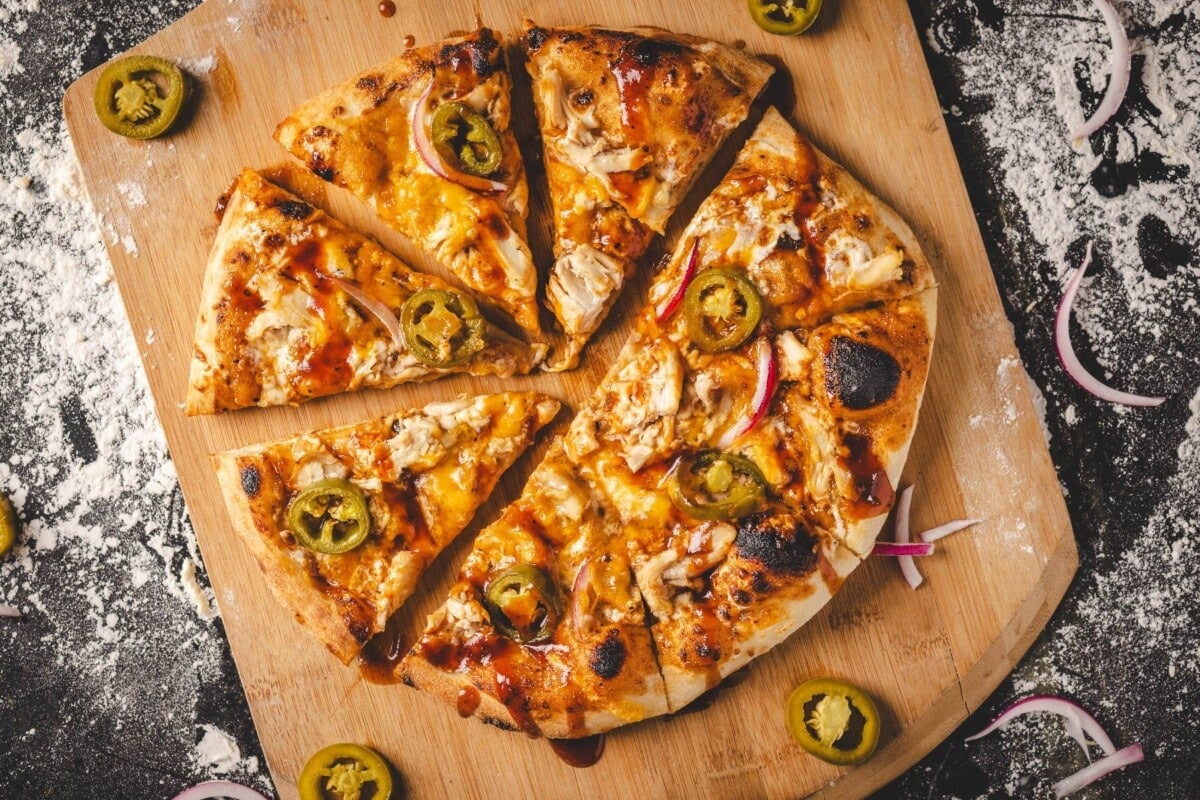 Baked chicken pizza on wooden peel.
