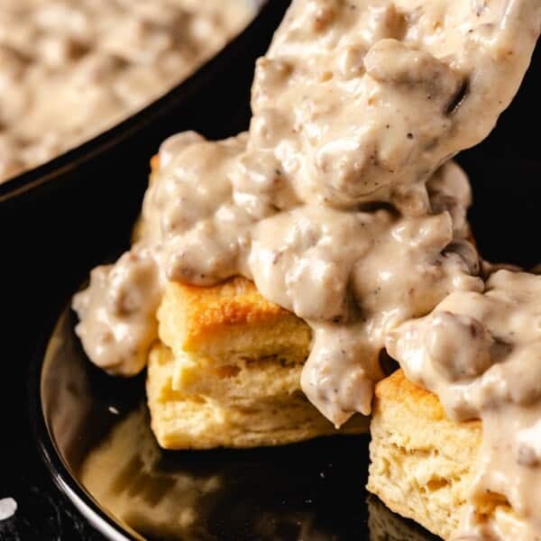 Biscuits and gravy on black plate.