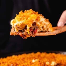 A scoop of chili Mac on a wooden spatula above a skillet.