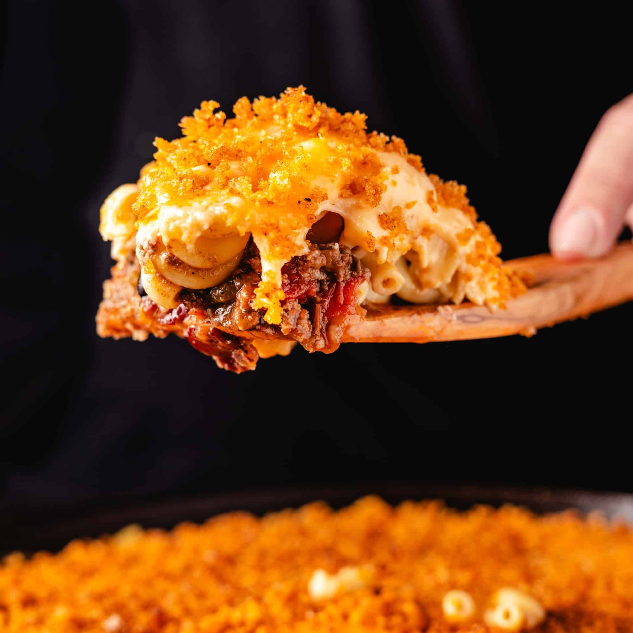 A ball of chili mac on a wooden spatula on a pan.