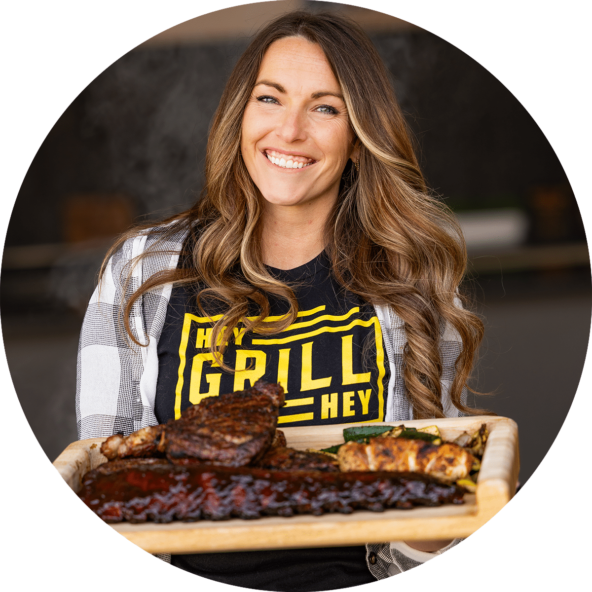 A profile picture of Hey Grill Hey found Susie Bulloch holding a platter filled with BBQ meats.