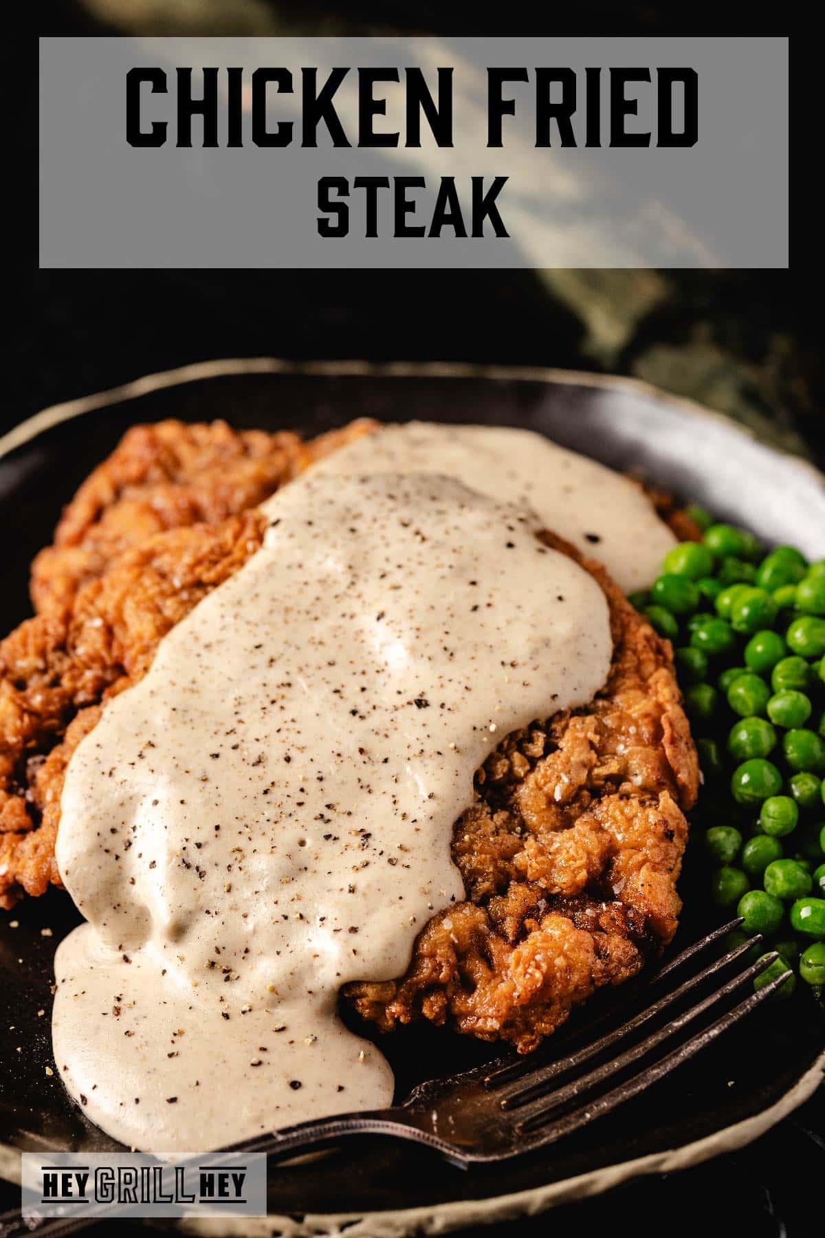 Breaded steak covered in gravy on metal plate with peas. Text reads "Chicken Fried Steak".
