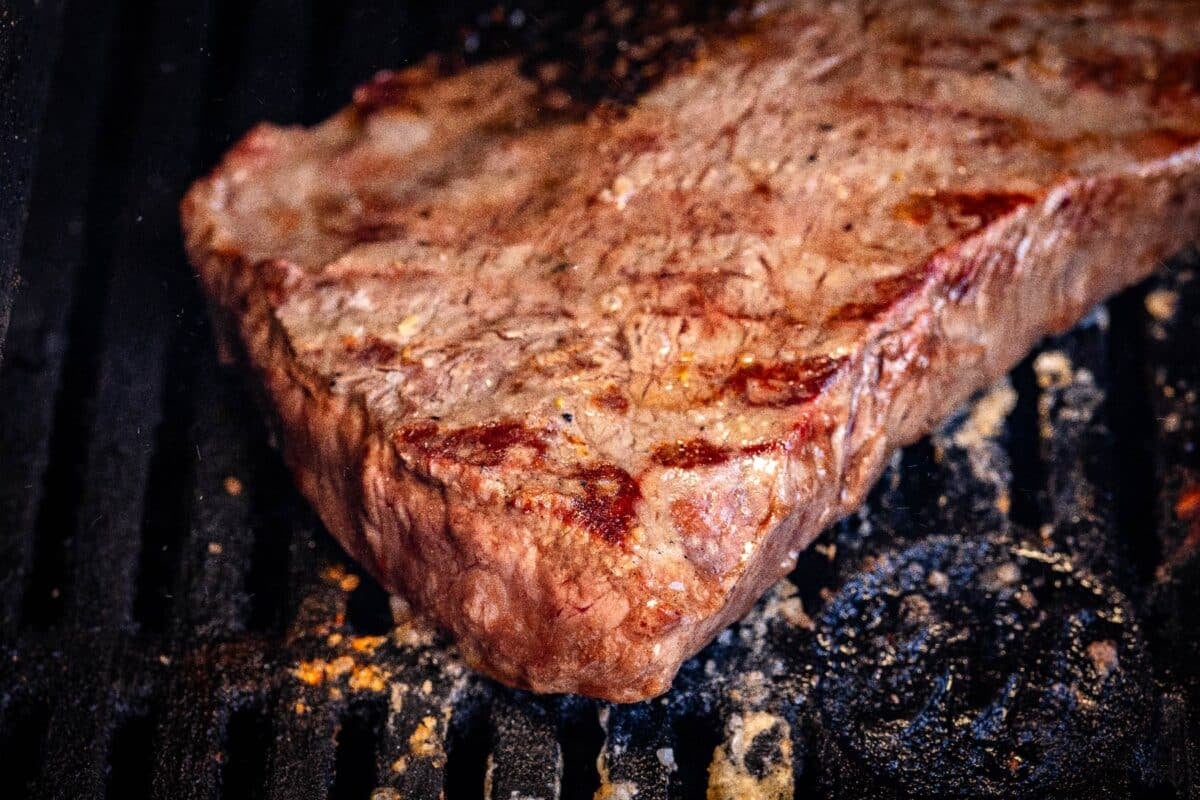 Flat iron steak on grill grates.