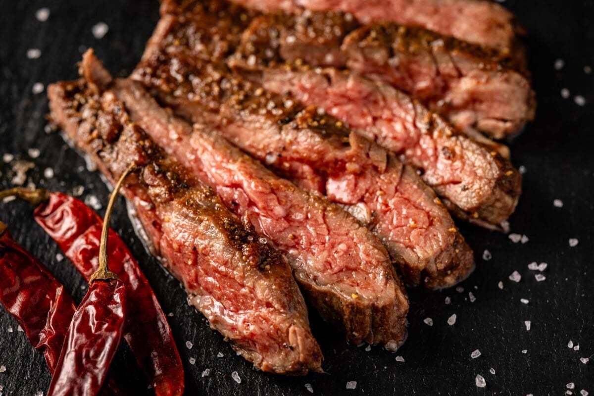 Sliced medium rare steak on serving platter.