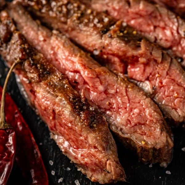 Sliced steak on serving platter sprinkled with flaky salt.