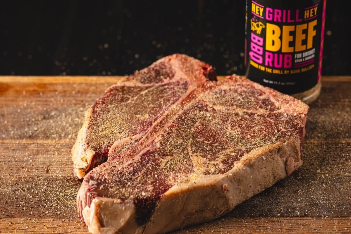 Seasoned beef on cutting board next to jar of beef rub.