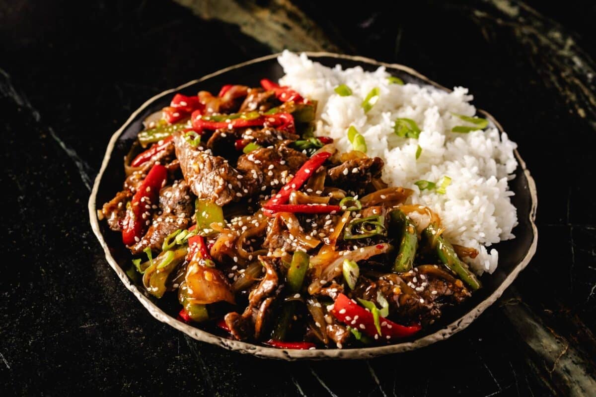 Asian style beef with peppers and white rice in bowl.