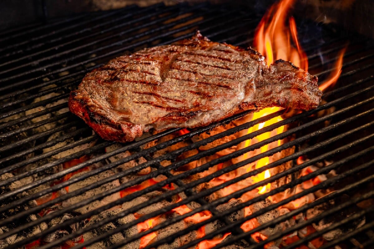 Steak on the grill over flames.