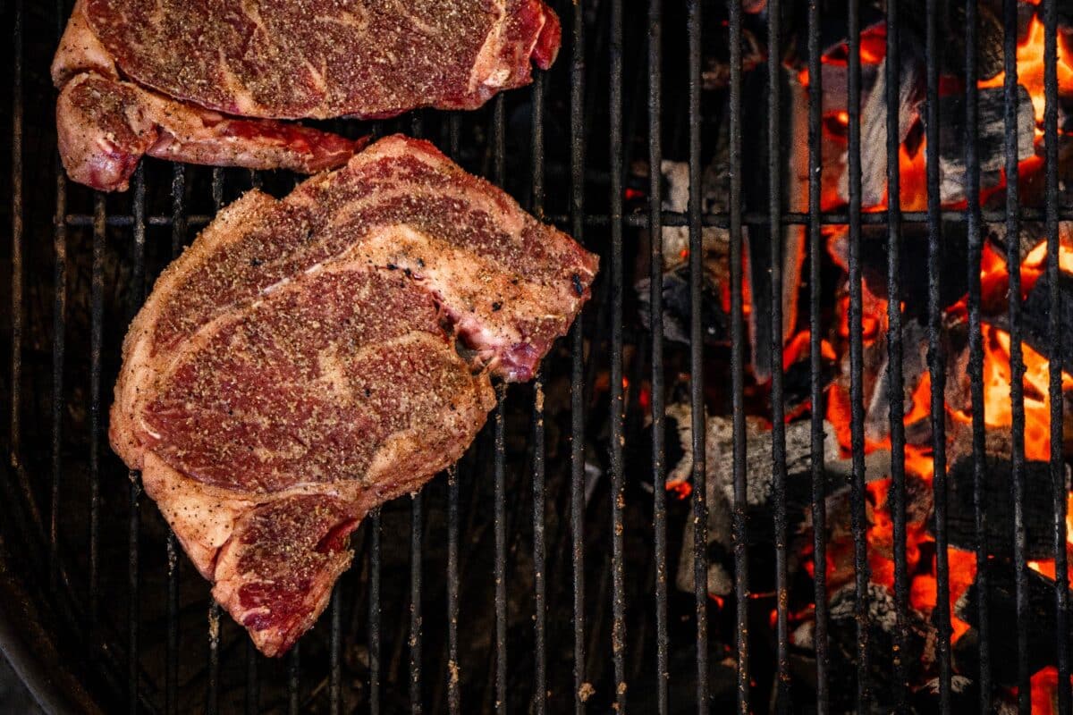 Ribeyes on grill grates over indirect heat.