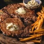 Sliced steak on serving platter with French fries. Text reads "Steak Frites with Mâitre d'Hôtel Butter".