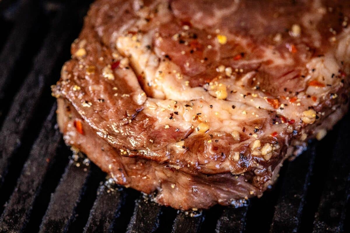 Steak on grill grates.