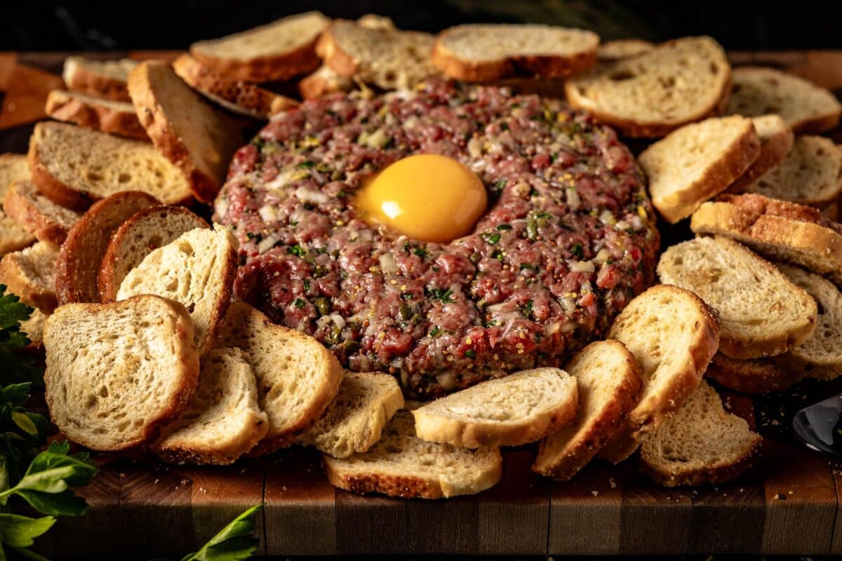 Tartare with egg yolk on top inside a circle of hard bread.