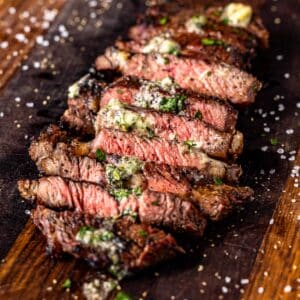 Sliced bison steak on wooden cutting board.