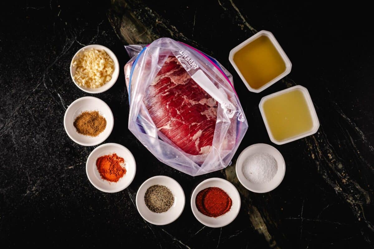 Raw beef flap in plastic bag and marinade ingredients in white bowls.