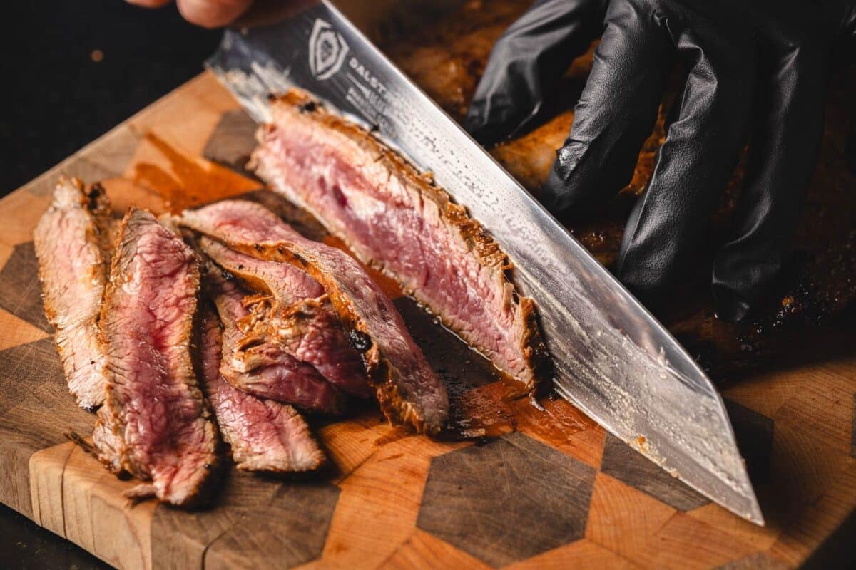 Knife slicing steak on cutting board for fajitas.