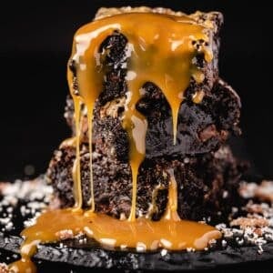 Brownies stacked and drizzled with caramel sauce.