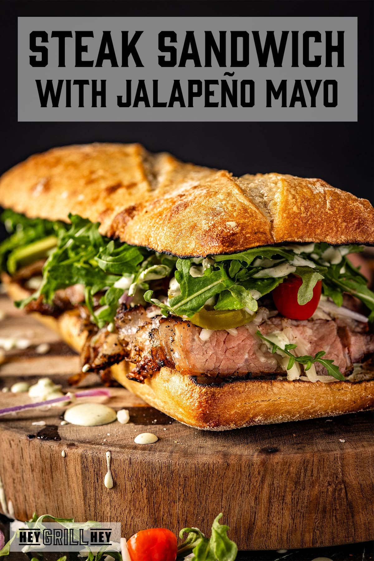 Steak sandwiches on wooden platter. Text reads "Steak Sandwich with Jalapeño Mayo".