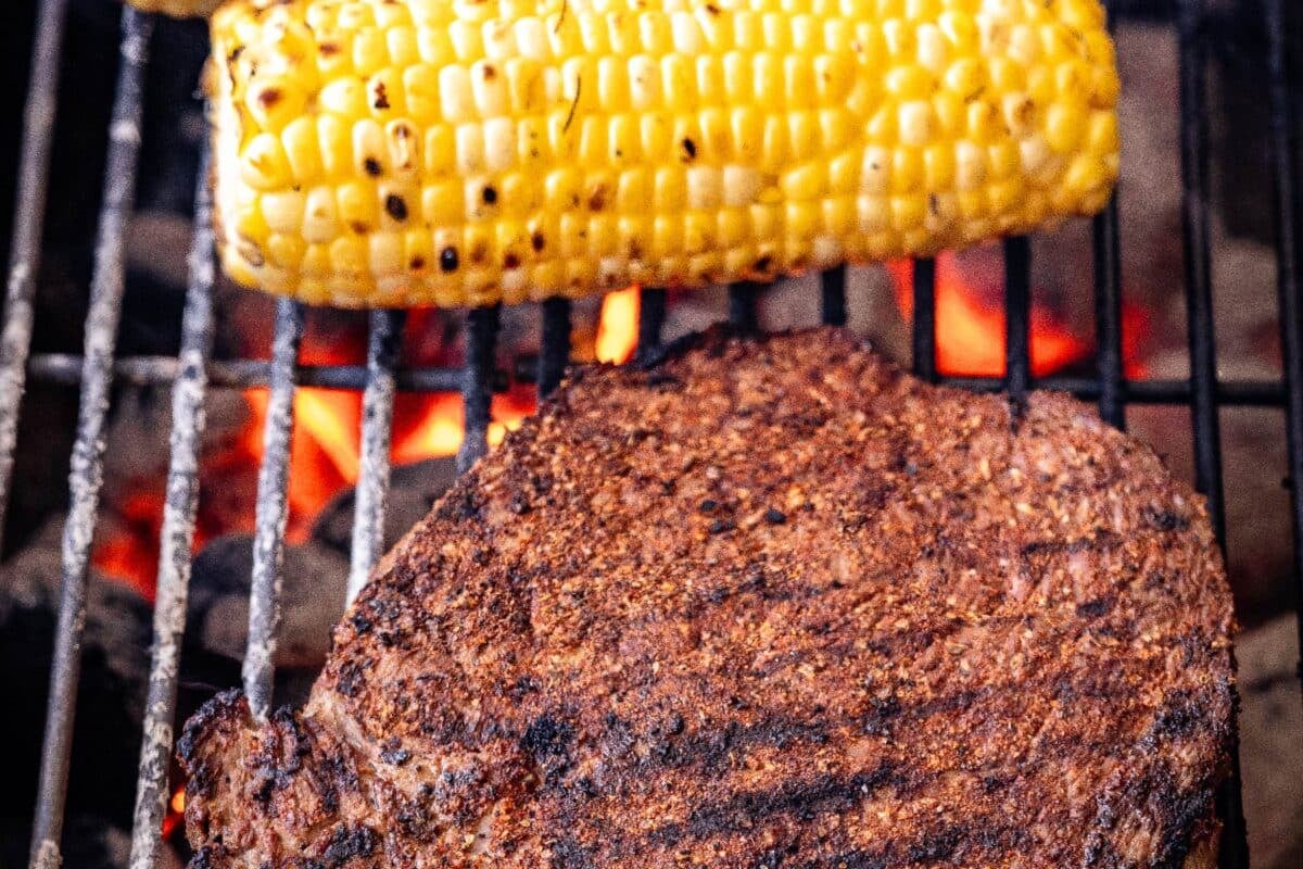 Corn and top sirloin on grill grates.