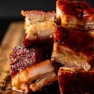 Sliced pork belly stacked on cutting board.