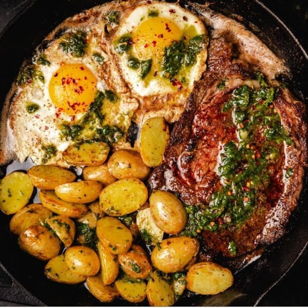 Steak, eggs, and potatoes in cast iron skillet.
