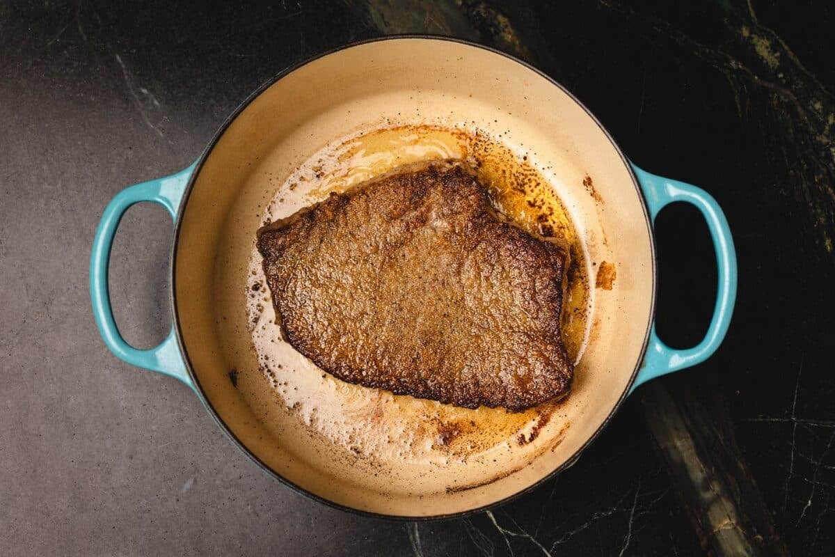 Seared steak in large pot.