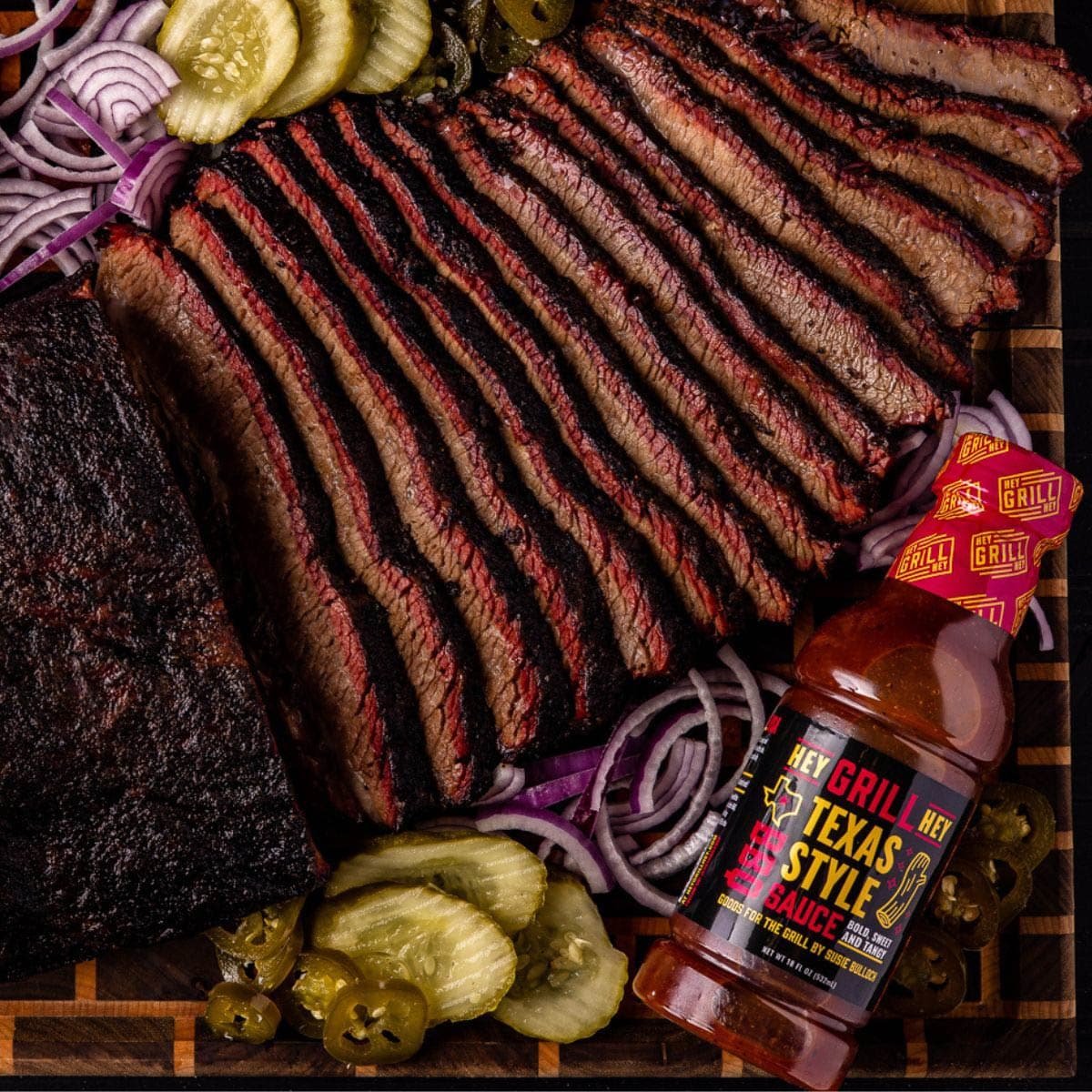 Texas Style BBQ Sauce bottle next to platter of sliced brisket.