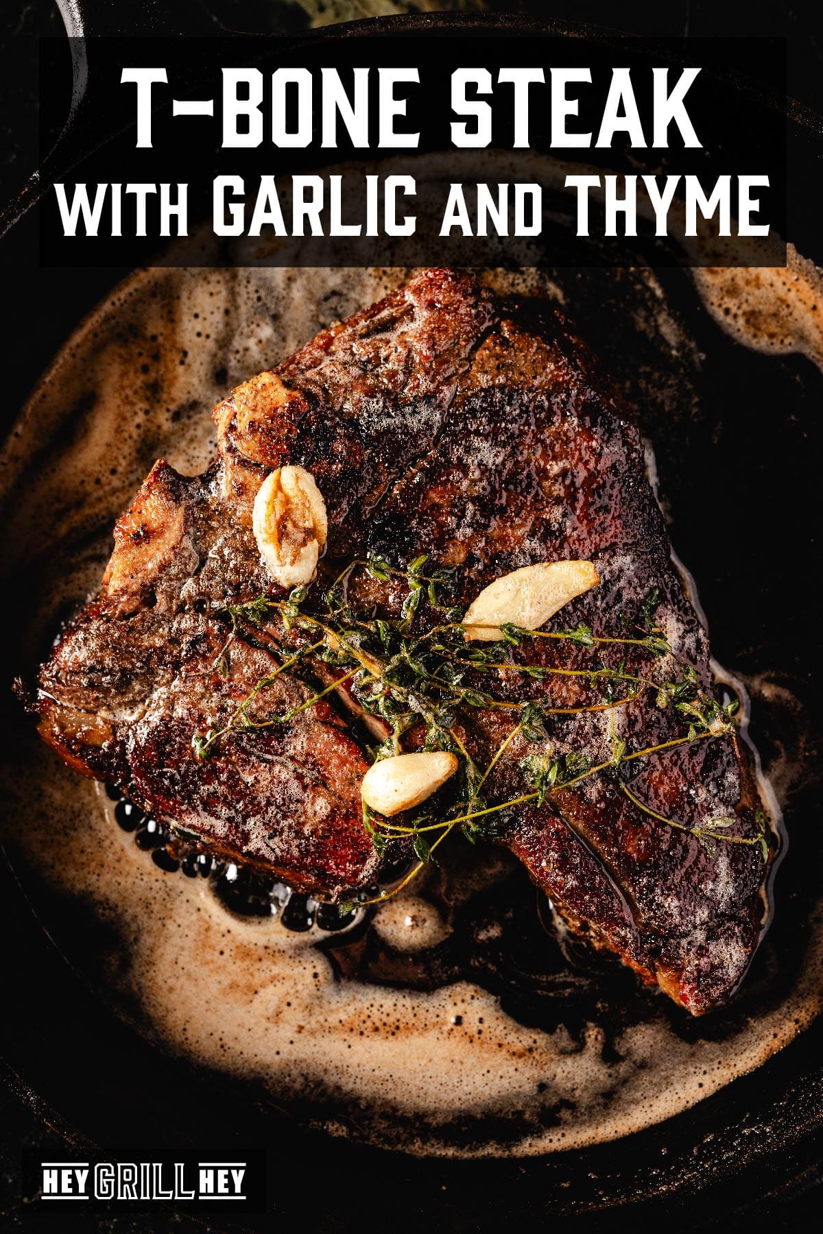 Steak on platter with garlic bulbs and thyme. Text reads "T-bone Steak with Garlic and Thyme".