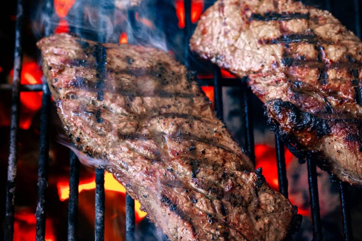 Grilled steaks on grates over hot charcoals.