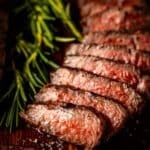 Sliced tri tip next to rosemary sprig.