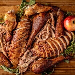 Platter of various smoked and sliced turkey meat with apples.