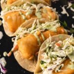 Baja fish tacos with cabbage slaw on black serving platter.