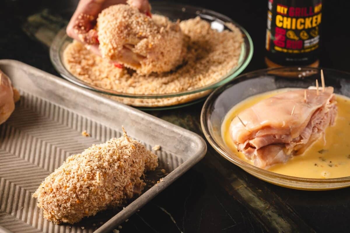 Panko breaded chicken breast on baking sheet, and chicken breasts in wet and dry dredges.