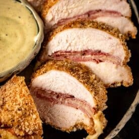 Chicken Cordon Bleu slices next to bowl of Dijon mustard sauce.