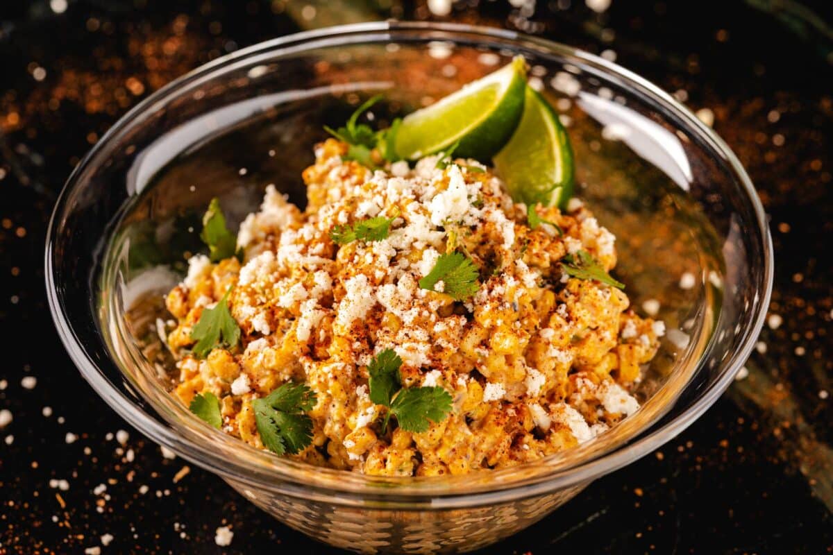 Corn Salad in glass bowl with lime wedge garnish.