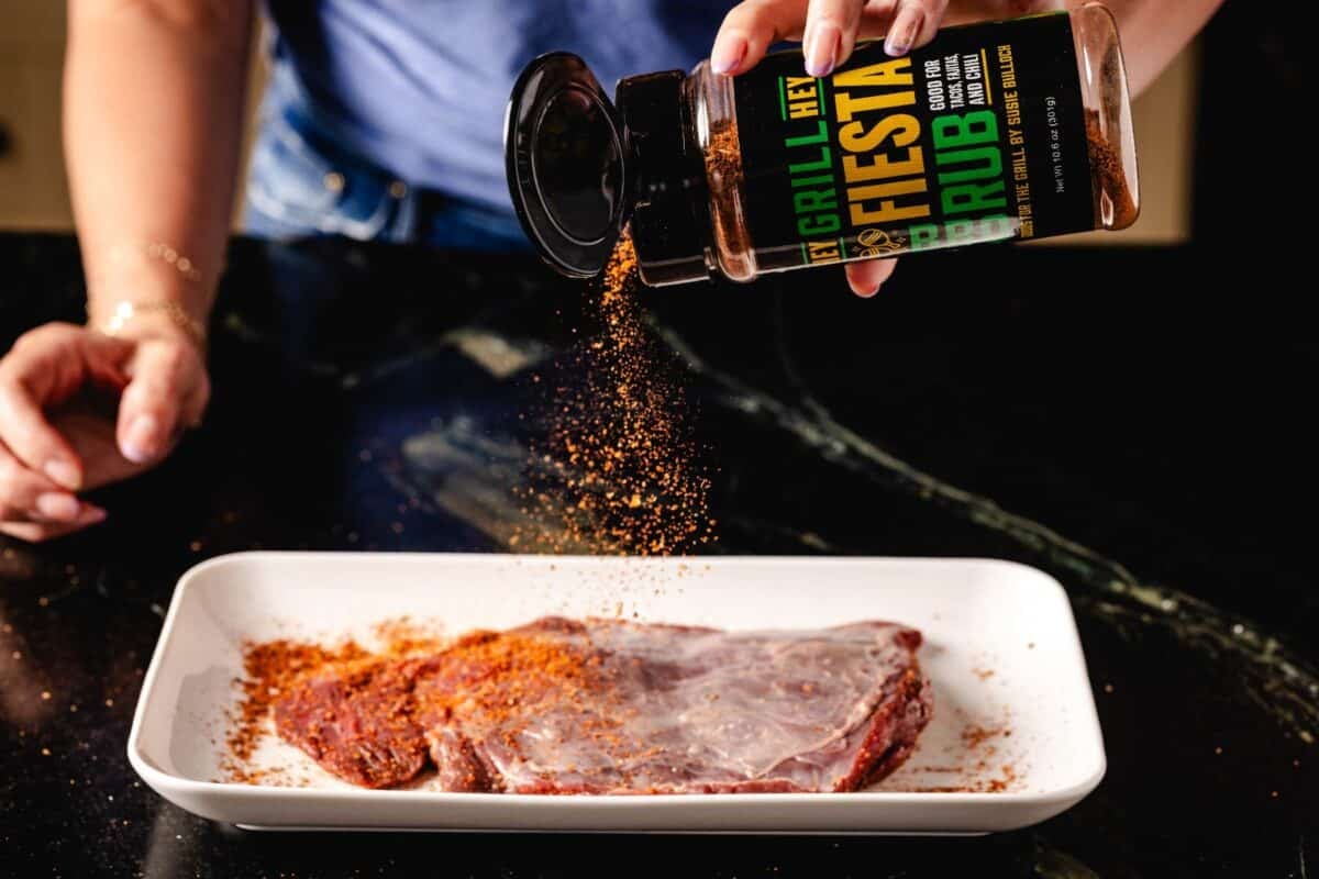 Carne asada on plate being sprinkled with seasoning.