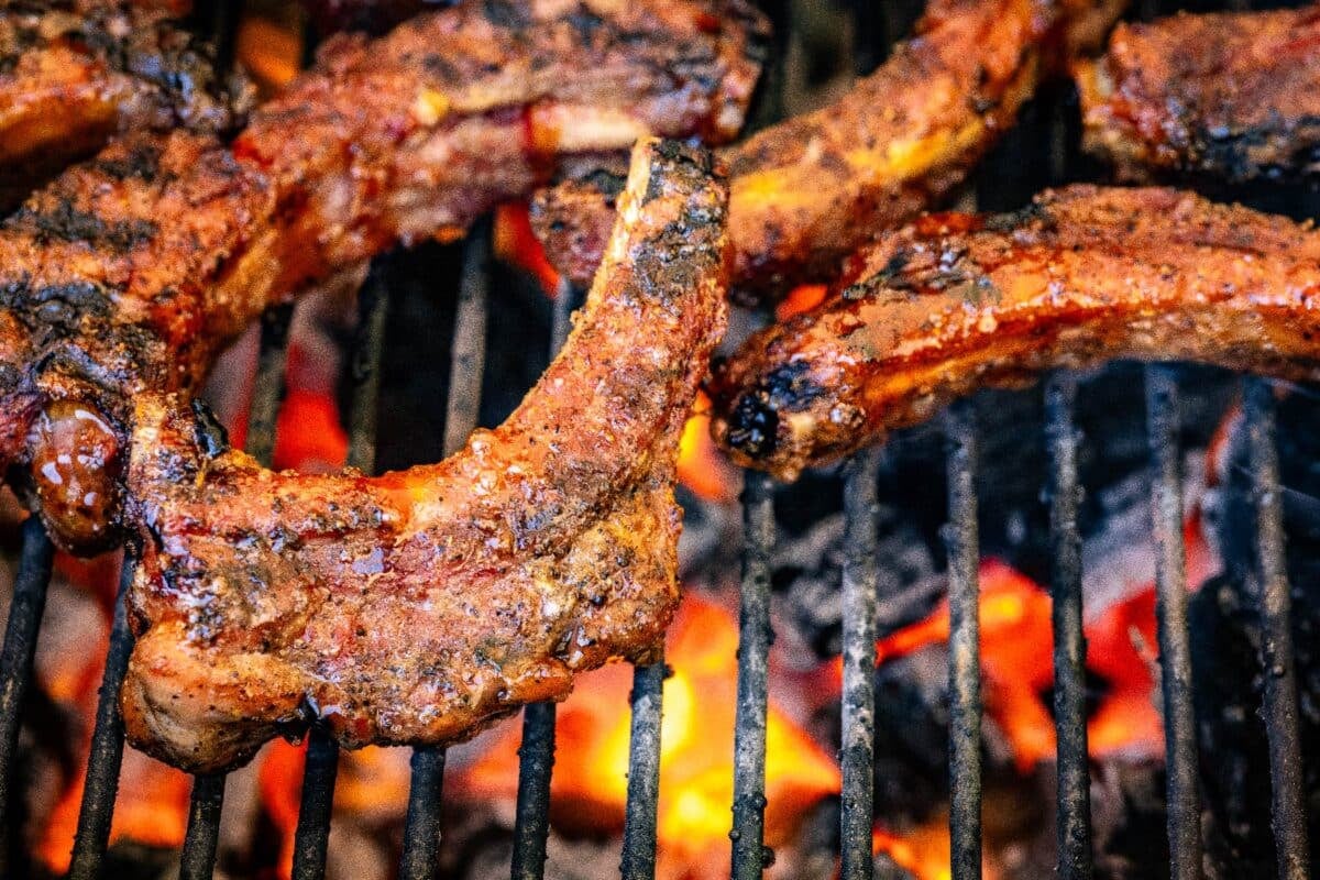 Grilled baby back ribs on grill grates over flames.