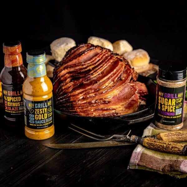 Double Smoked Ham with it ingredients and sides on a black surface.