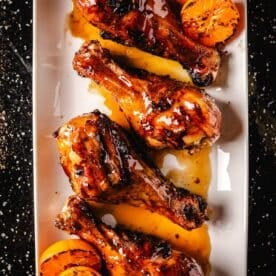 Spiced Citrus chicken legs on white platter.