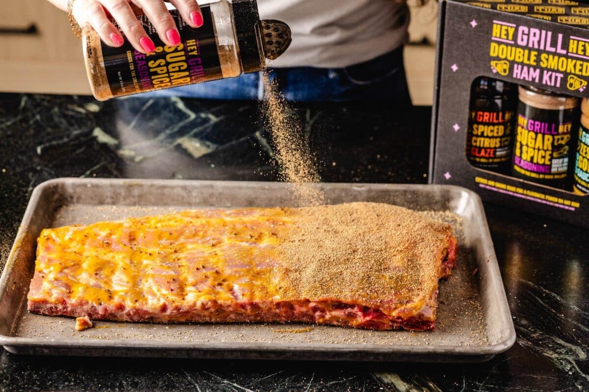 Ribs on baking sheet being seasoned with Sugar & Spice Rub.