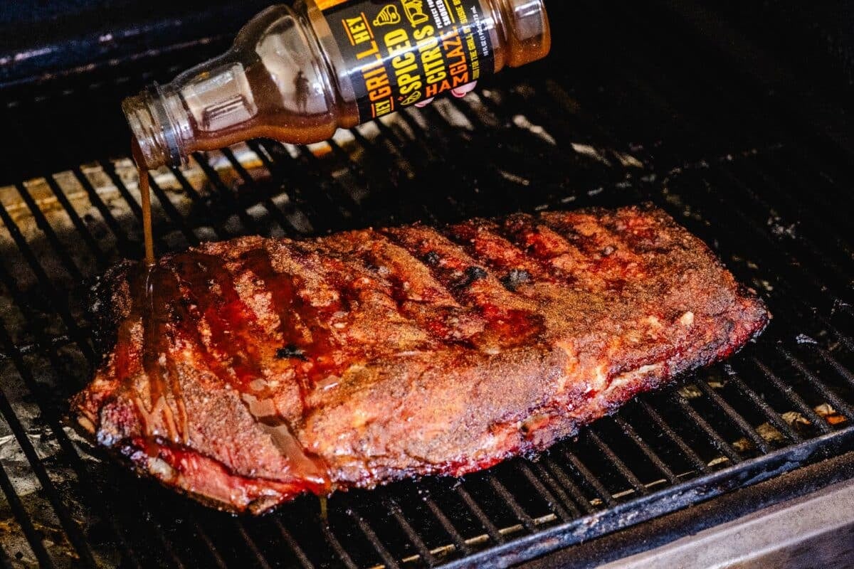 Spare ribs on the smoker being coated with Spiced Citrus BBQ Glaze.