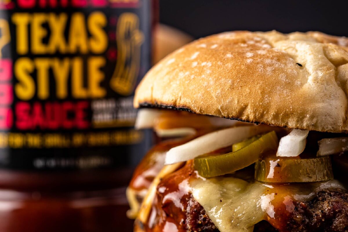 Brisket burger in front of a bottle of Texas Style BBQ Sauce.