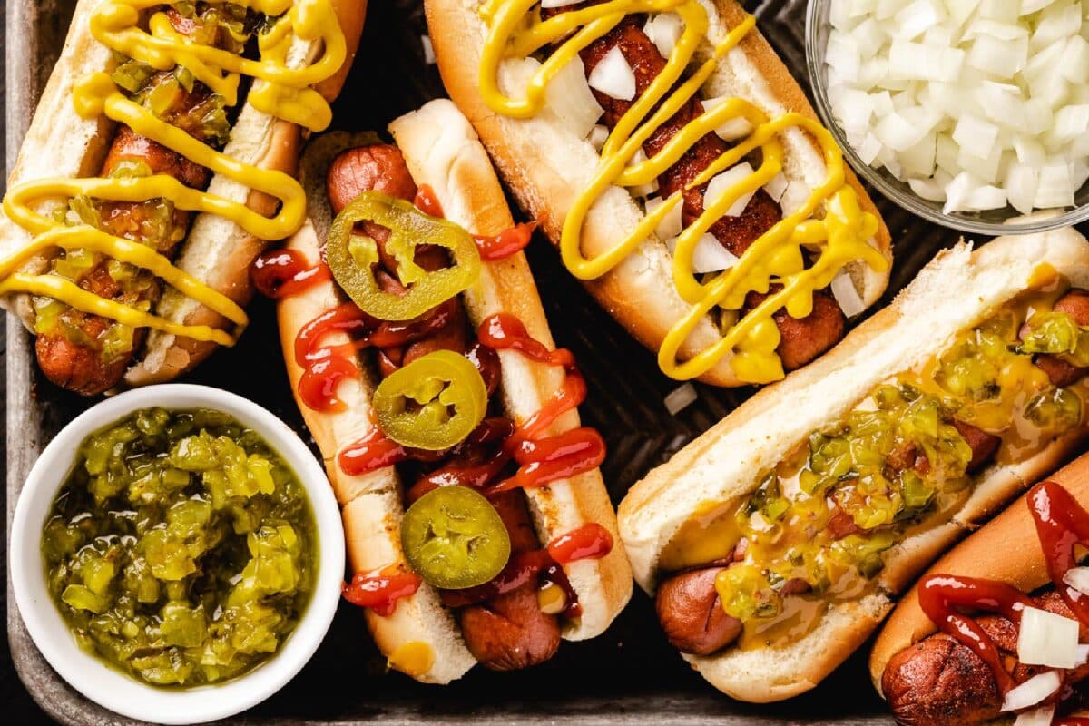 Various hot dogs with toppings, including Zesty Gold Sauce.